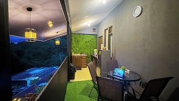 A narrow hallway with a green wall, a small seating area with a laptop, and a view of a parking lot outside.