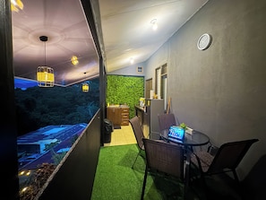 Un couloir étroit avec un mur vert, un petit coin salon avec un ordinateur portable et une vue sur un parking à l’extérieur.