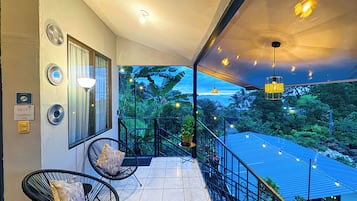 A balcony with a view of the ocean, a chair, and a railing.