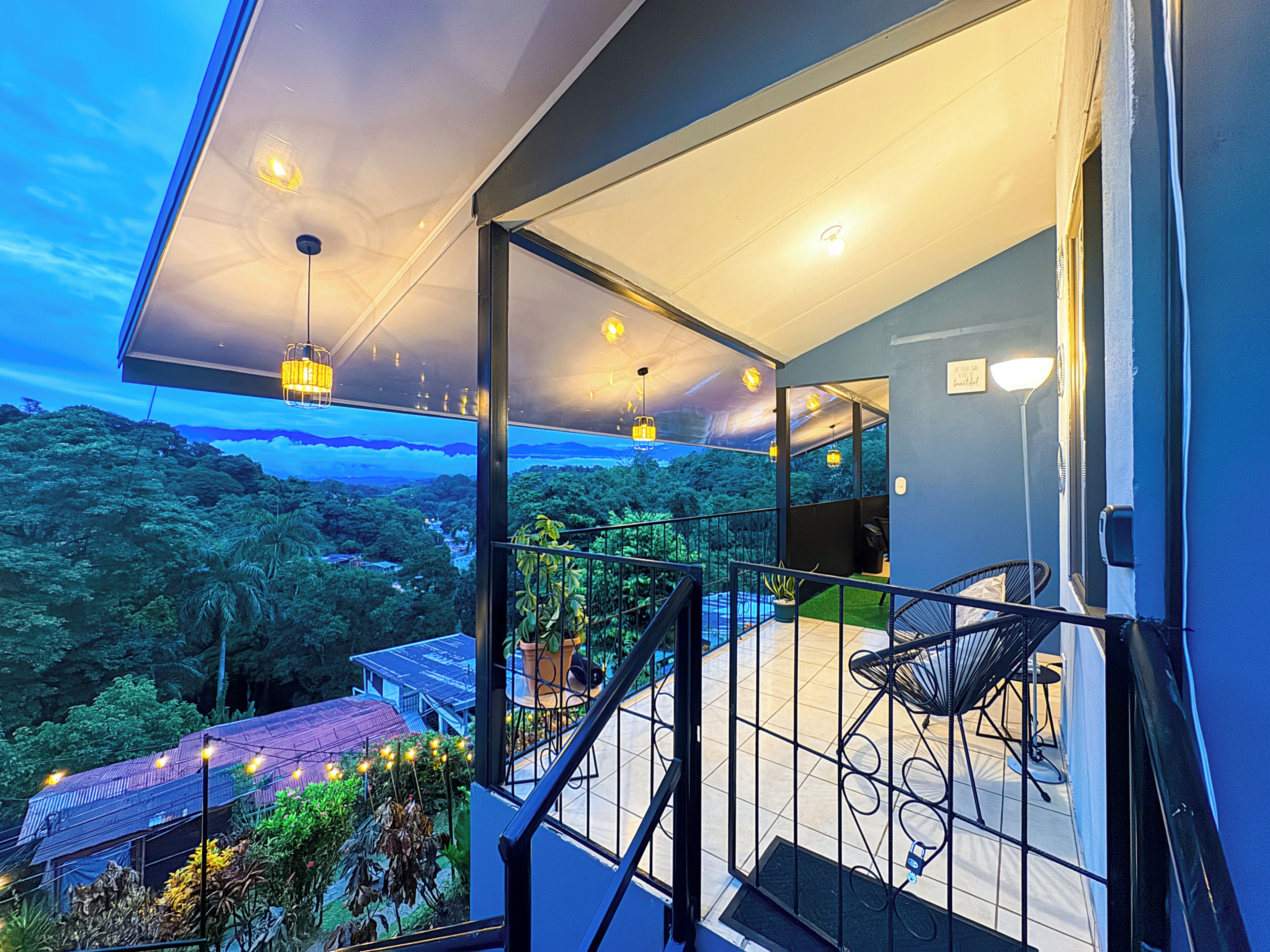 Un balcon donnant sur un paysage verdoyant, avec une chaise et une table.