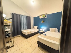 A hotel room with two single beds, a small bedside table with a lamp, a wall-mounted air conditioner, and a shelf with toiletries. - Tropical Hideaway Villa, Manuel Antonio, Quepos. (Manuel Antonio)