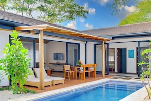 Ein moderner Poolbereich im Freien mit einer Pergola, Liegestühlen und einem Esstisch.