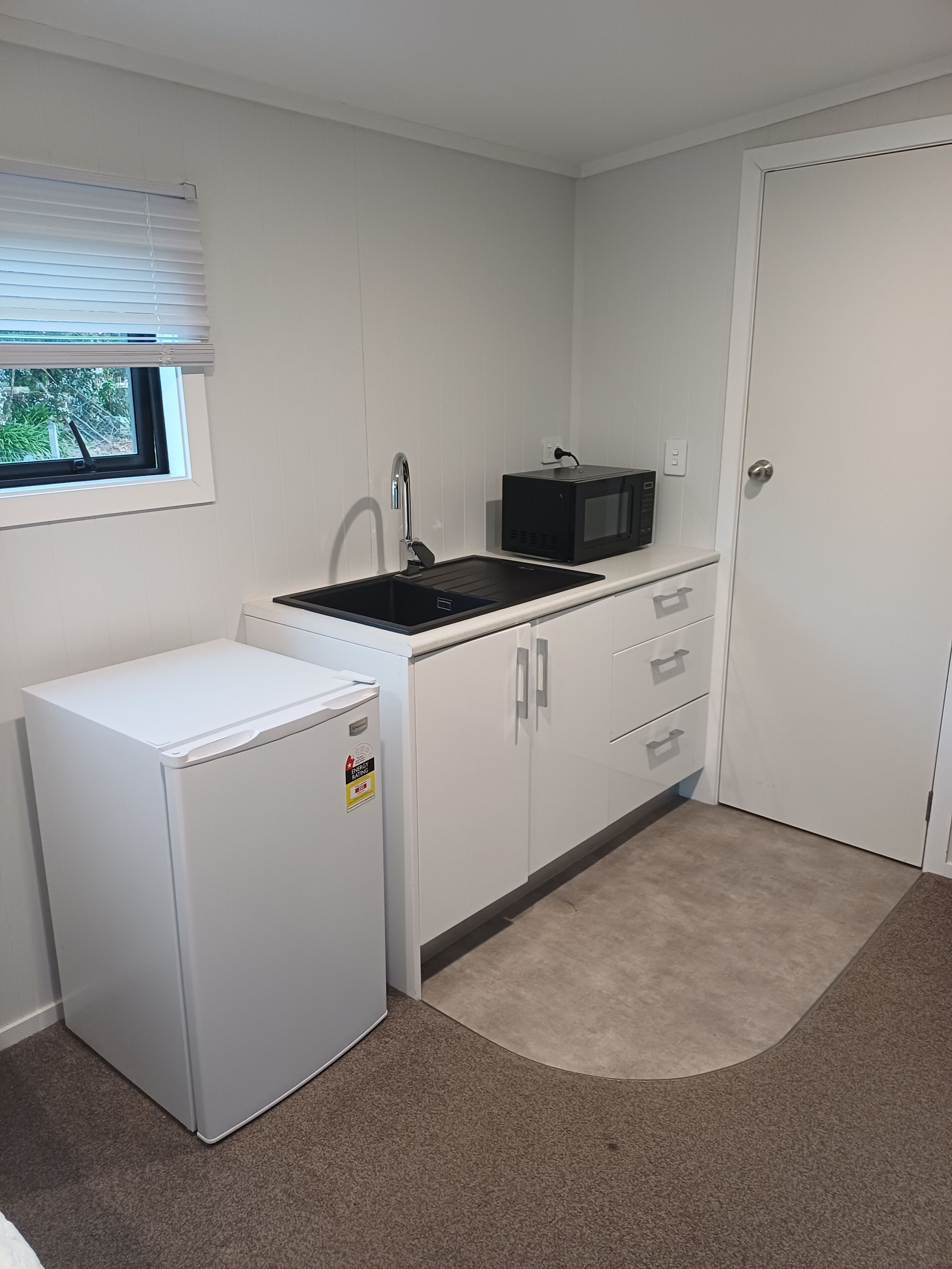 A compact kitchen with a refrigerator, a sink, and a microwave.