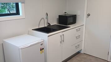 A compact kitchen with a refrigerator, a sink, and a microwave.