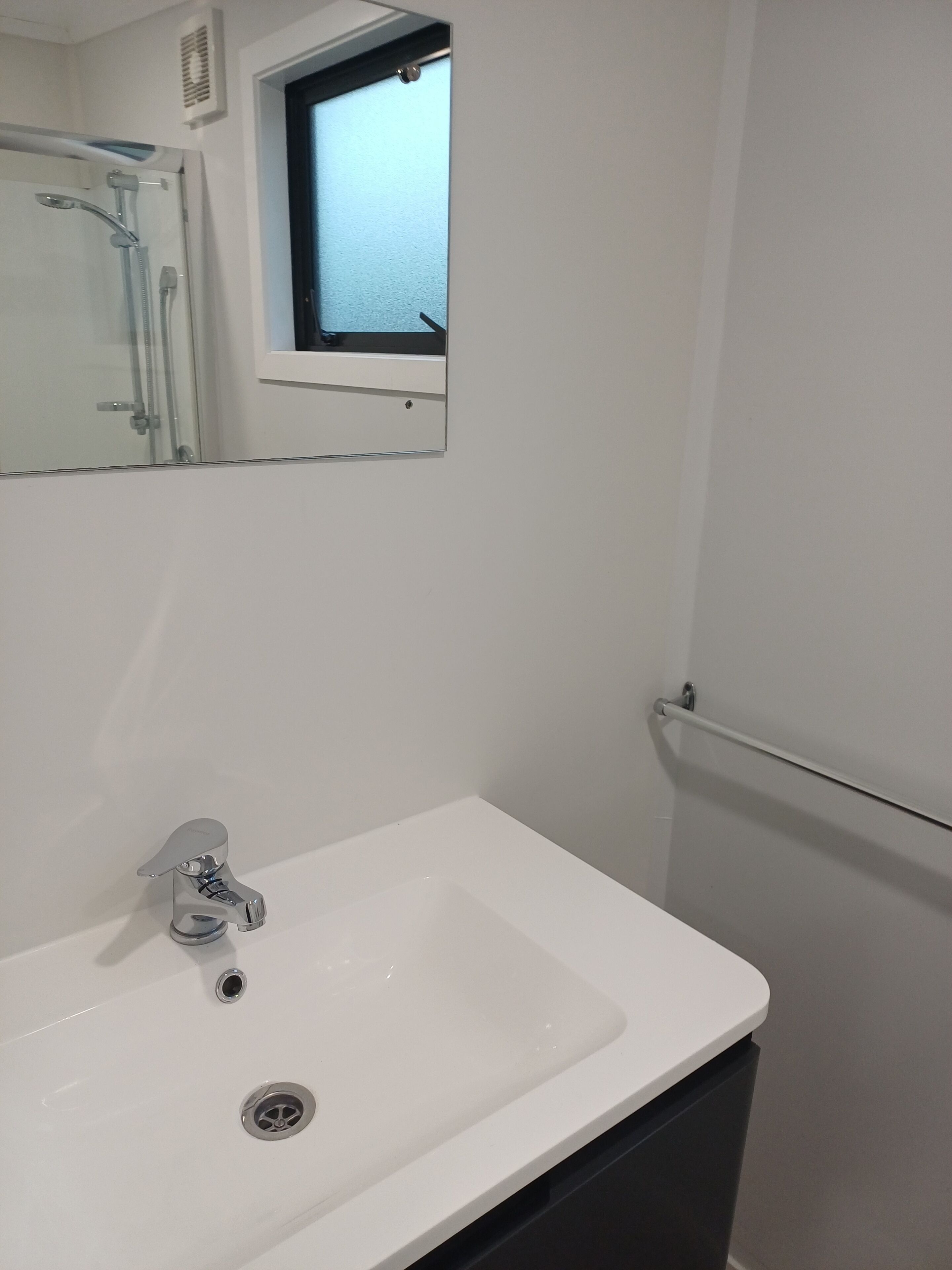 A bathroom with a white sink, a mirror, and a window.