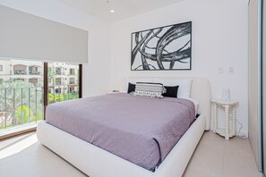 Een slaapkamer met een groot bed, nachtkastje, een kunstwerk aan de muur en uitzicht op het omliggende landschap.