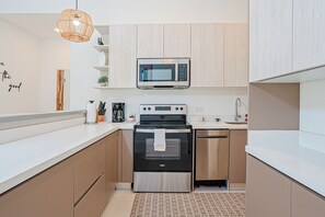 Een moderne keuken met roestvrijstalen apparatuur, houten kastjes en een wit aanrecht.