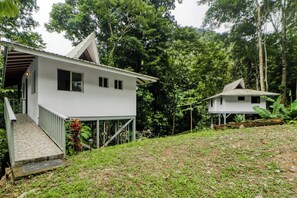 Une maison blanche à deux étages, dotée d’un porche et d’un petit jardin.