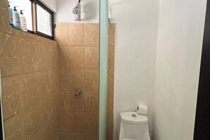 A bathroom with a shower, toilet, and a shelf with toiletries. - Club Voca Studio w/ Resort-Style Pool + Near Beach (Playas del Coco)