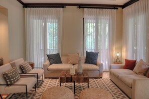 A living room with two sofas, a coffee table, and a lamp. - Hacienda Pinilla Villa: Lap Pool, Near Beaches (Tamarindo)