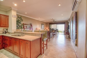 A spacious kitchen with granite countertops, wooden cabinets, and a central island. - Stunning 2BR Oceanview 4th-Floor | Balcony (Flamingo Beach)