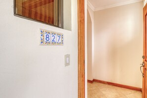 A hallway with a door, a wall-mounted number plate, and a light switch. - Stunning 2BR Oceanview 4th-Floor | Balcony (Flamingo Beach)