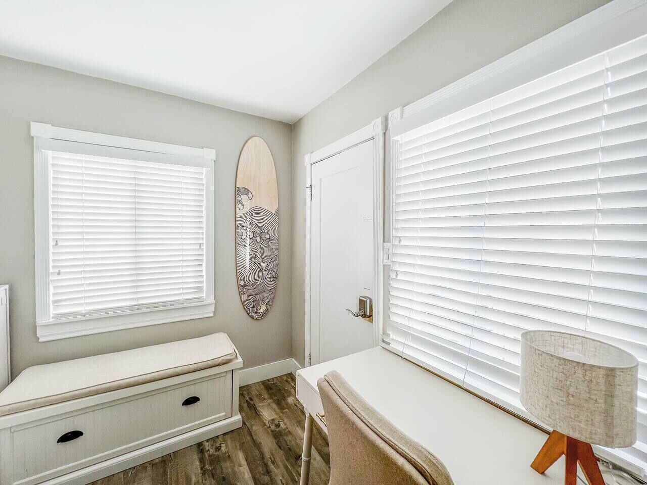A room with a bench, a desk, and a door.