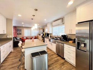 A modern kitchen with white cabinets, stainless steel appliances, and a central island with seating. - Retro Lounge | Family-friendly, Arcade Games+Patio (San Diego)