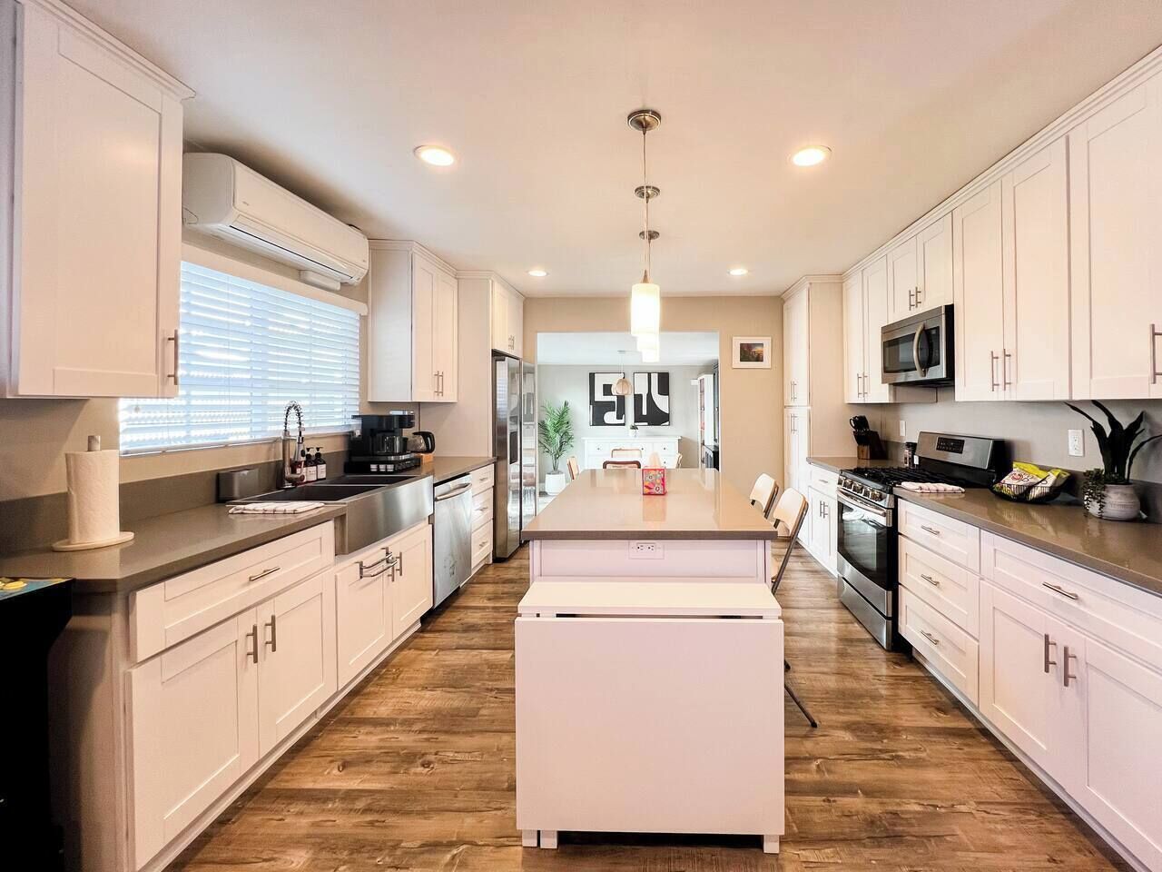 A modern kitchen with white cabinetry, a central island, and a wood floor.