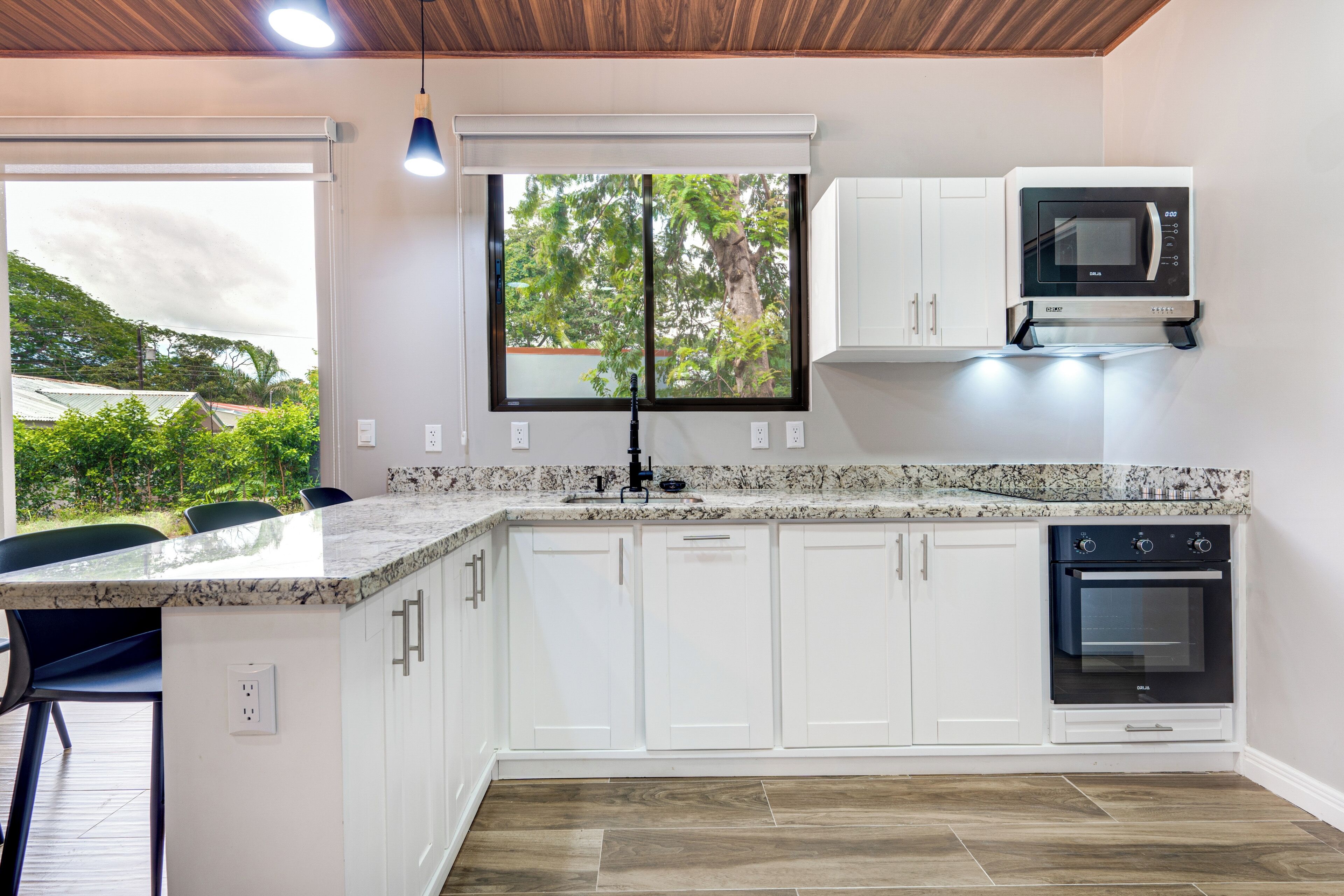 A modern kitchen with white cabinetry, a built-in oven, and a microwave.
