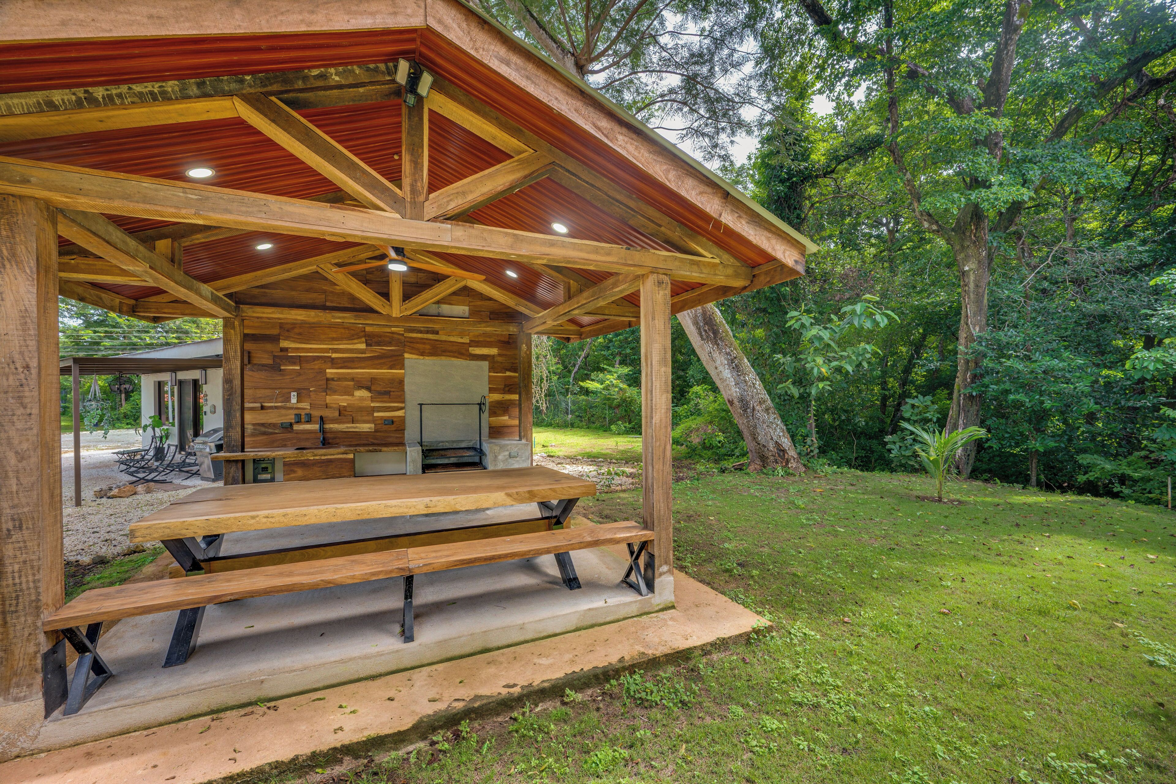 Un pavillon en bois doté d’un barbecue intégré et d’un espace détente avec des sièges.