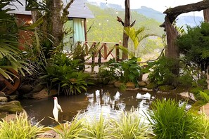 Un jardín tranquilo con un estanque, un puente de madera y un pequeño edificio.