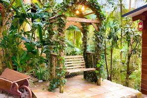 A garden with a wooden bench, a small wheelbarrow, and a rustic wooden structure.