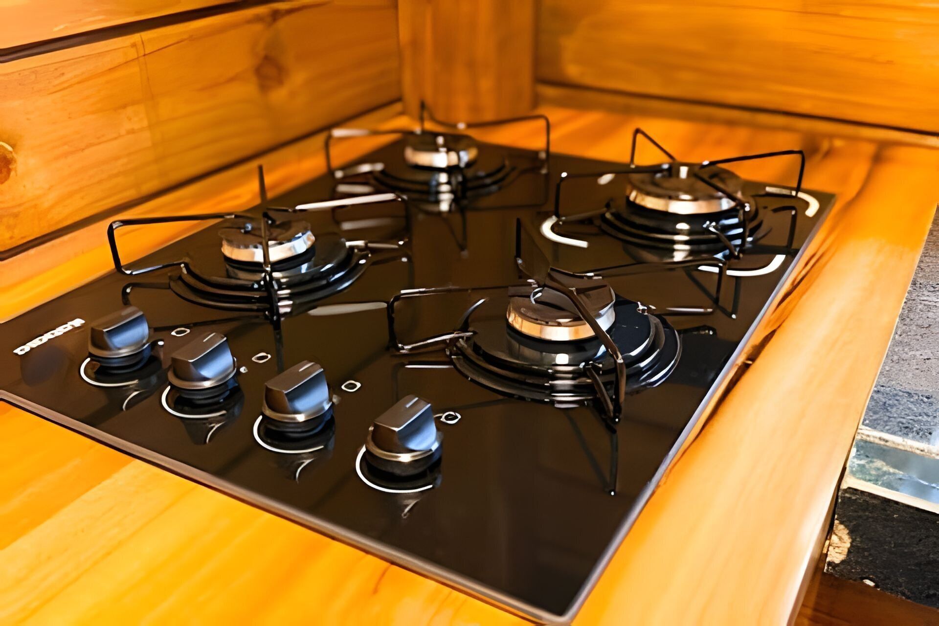 A black stovetop with four burners and a control knob on each.