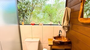 Un baño con inodoro, lavabo y ventana con vistas a la vegetación.
