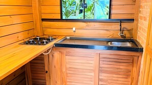 Una cocina compacta con armarios de madera, una estufa a gas y un lavamanos.