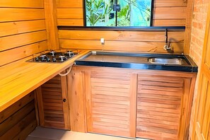 A compact kitchen with wooden cabinets, a gas stove, and a sink. - ASA Sunset Valley Cabana do Capitao Vista (Jose Boiteux)