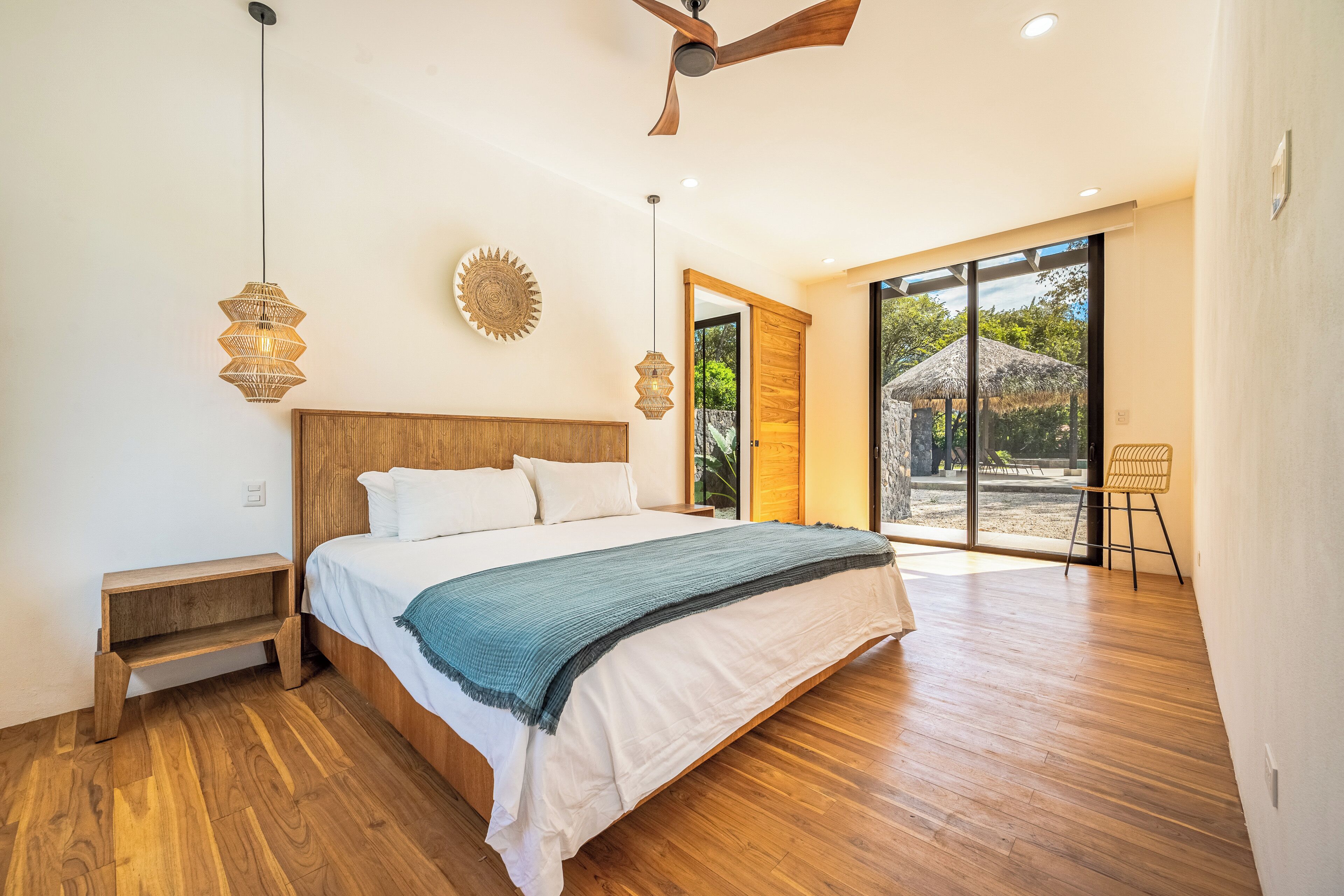 A modern bedroom with a wooden bed, a large window, and a view of the outdoors.
