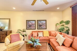 A living room with a sofa, armchairs, a coffee table, and two wall-mounted paintings. - Walkable Coco Beach Condo w/ Balcony, Pool (Playas del Coco)