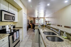 A kitchen with granite countertops, stainless steel appliances, and a large window. - Walkable Coco Beach Condo w/ Balcony, Pool (Playas del Coco)