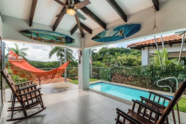 A poolside area with a hammock, rocking chairs, and a view of the pool and greenery. - Villa Sol Resort Gem w/ Soaking Pool & Views! (Playa Hermosa)