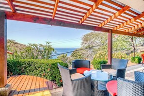 Een terras buiten met rieten meubilair en uitzicht op zee.