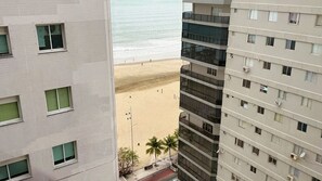Ein Hochhaus mit mehreren Etagen, großen Fenstern und Balkonen mit Blick auf einen Strand.