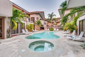 A pool area with lounge chairs and palm trees. - Sunny 2BR: Balcony, Pool, Kitchen, Walk to Beach (Playa Ocotal)