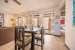 A dining area with a table and chairs, a sofa, a clock, and a wall with a motivational quote. - 3 Mi to Tamarindo & Beach: Cozy 2BR Home (Tamarindo)