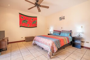 Ein Schlafzimmer mit einem Bett, einem Deckenventilator, einer Wandweberei und einem Schild.