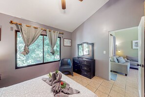 A bedroom with a bed, a dresser, a chair, a mirror, and a view of a garden through the window. - Playa Ocotal Condo w/ Pool: Walk to the Beach! (Playa Ocotal)