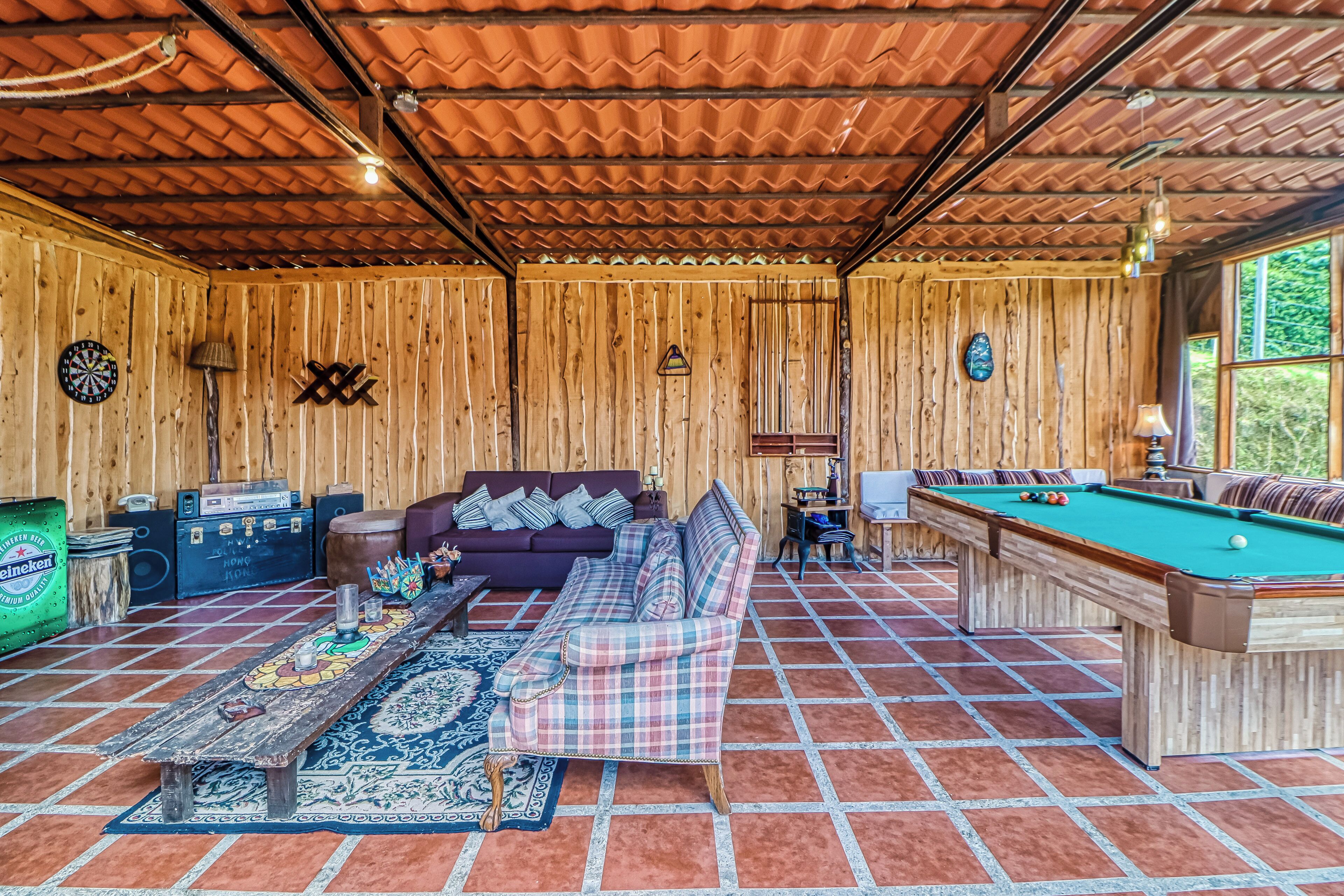 A cozy room with a pool table, a sofa, and a dartboard.