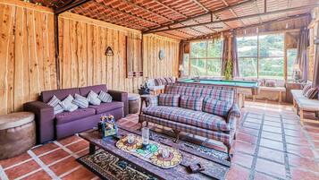 A wooden interior with a billiards table, sofas, and a pool table.