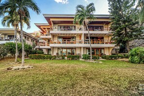 A multi-story hotel with a flat roof, balconies, and a well-maintained lawn. - Ideal 2BR Oceanfront 2nd-Floor | Balcony (Flamingo Beach)