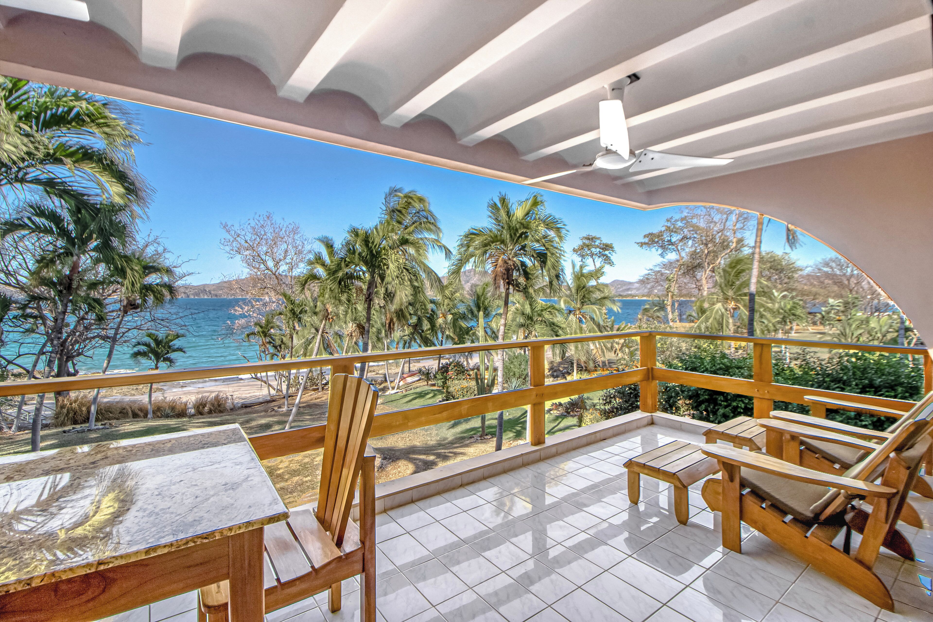 A balcony with a view of the sea and palm trees.
