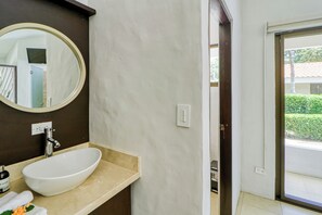 A bathroom with a white sink, a mirror, and a door leading outside. - Studio w/ Resort-Style Pool, Walk to Beach! (Playas del Coco)