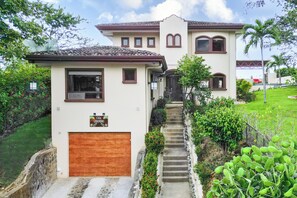 A two-story house with a garage, a staircase leading to the entrance, and a well-maintained garden. - Private Pool, Mtn-View Veranda! 3BR Carrillo Home (Playas del Coco)