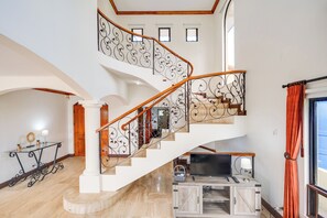 Ein mehrgeschossiges Interieur mit Treppe, Flachbildfernseher und Holzschrank.