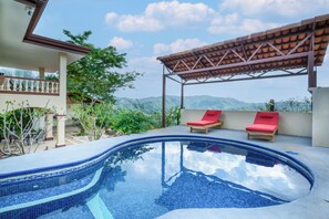 A swimming pool with two red lounge chairs under a pergola, surrounded by greenery and overlooking a mountainous landscape. - Private Pool, Mtn-View Veranda! 3BR Carrillo Home (Playas del Coco)