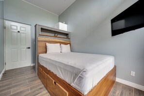 Une chambre à coucher avec un cadre de lit en bois, un matelas blanc et une tête de lit intégrée.