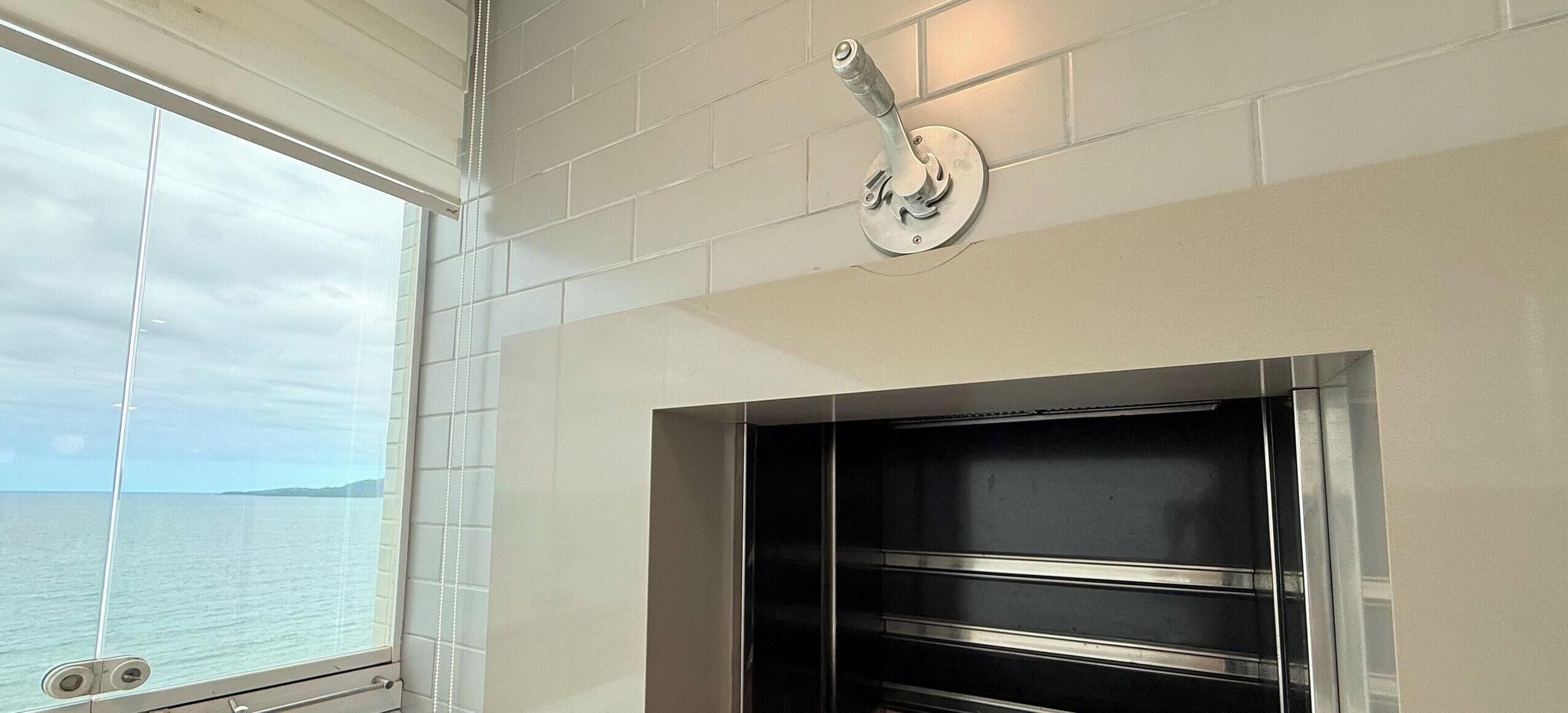 A bathroom with a window, a towel rack, and a built-in oven.