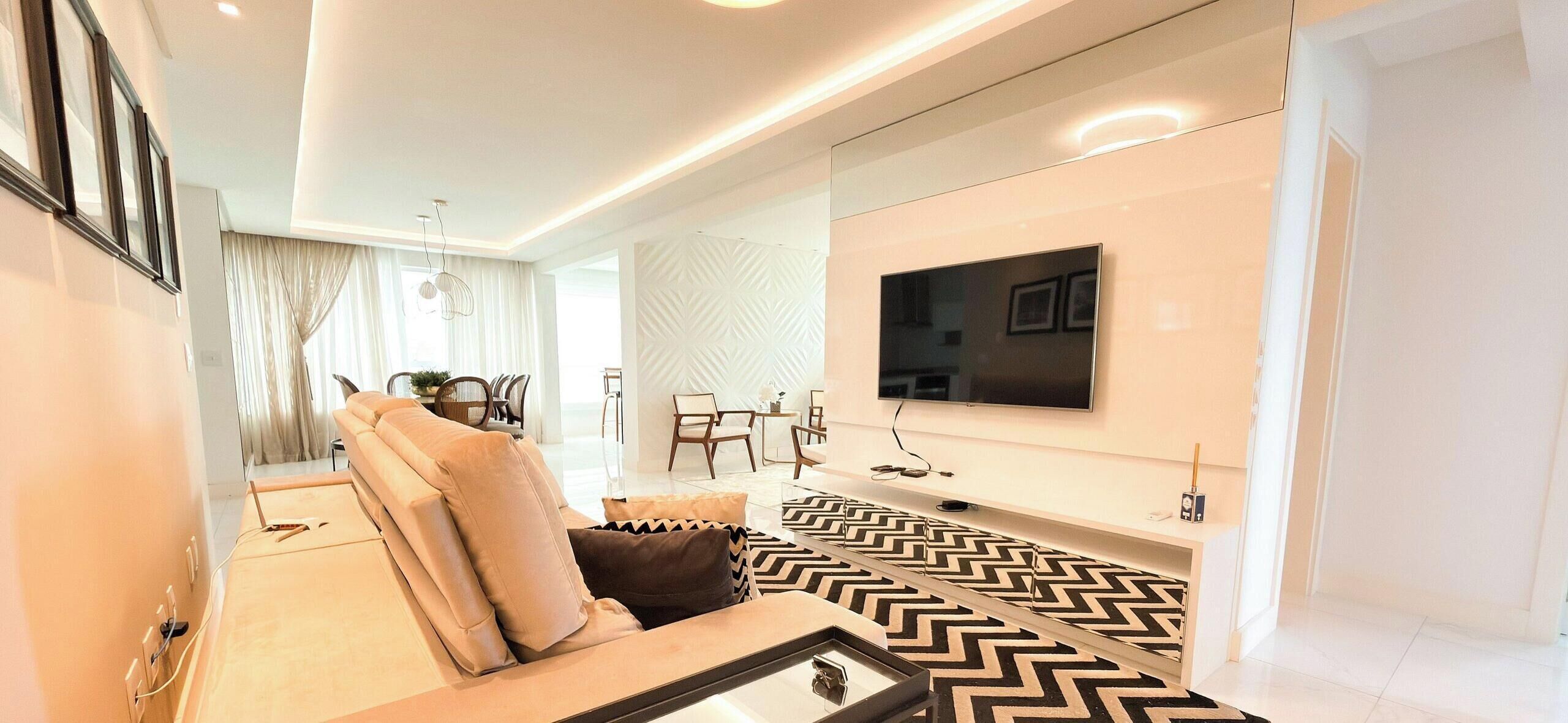 A modern living room with a sofa, a television mounted on the wall, and a patterned rug.