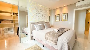 A modern bedroom with a large bed, a walk-in closet, and a decorative wall panel. - ASA Cobertura Luxo 2QT Meia Praia Hidro (Itapema)