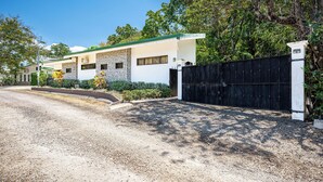 Uma casa moderna de dois andares com entrada de cascalho e portão preto.
